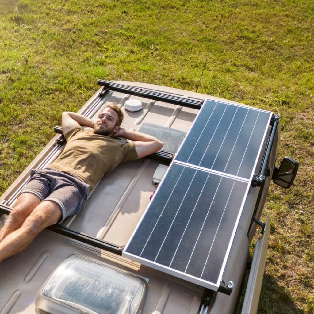 solar panels on top of campervan roof with a man lying next to them